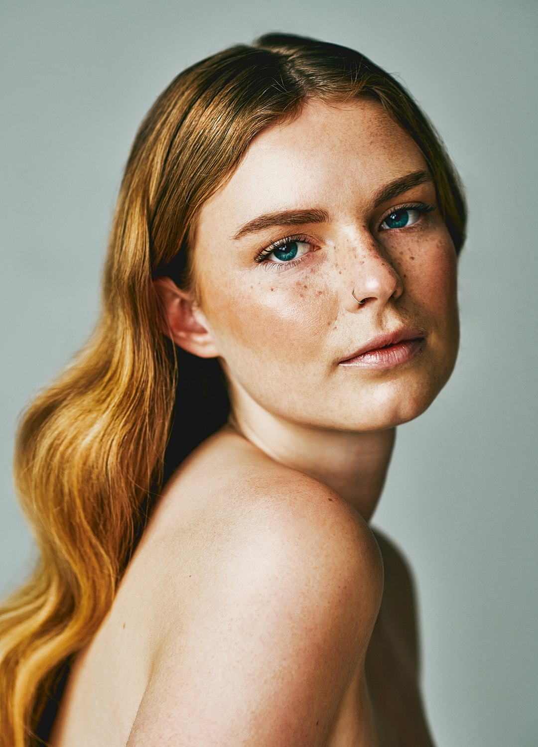 Greenfield SkinPen model with green eyes touching her chin.