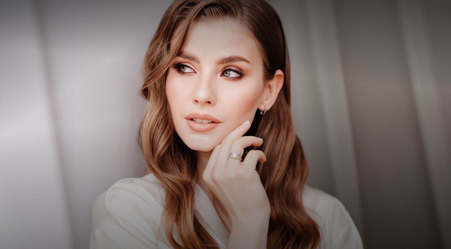 Woman touching her chin, elegant hairstyle and makeup.